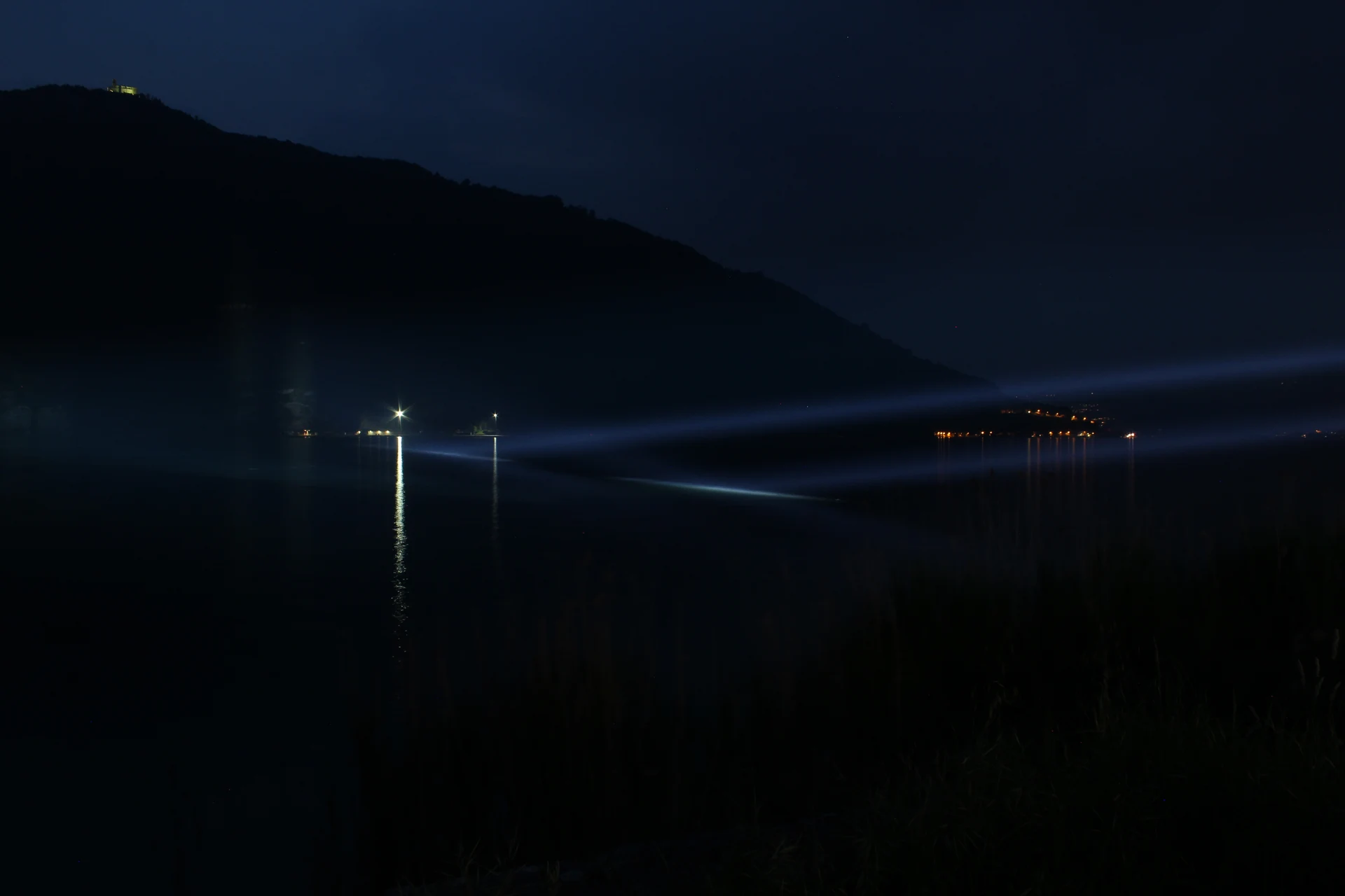 Installazione luminosa su un ponte del Lago d'Iseo, riflessa nell'acqua al tramonto — SUONO E LUCE, Seriate (Bergamo)