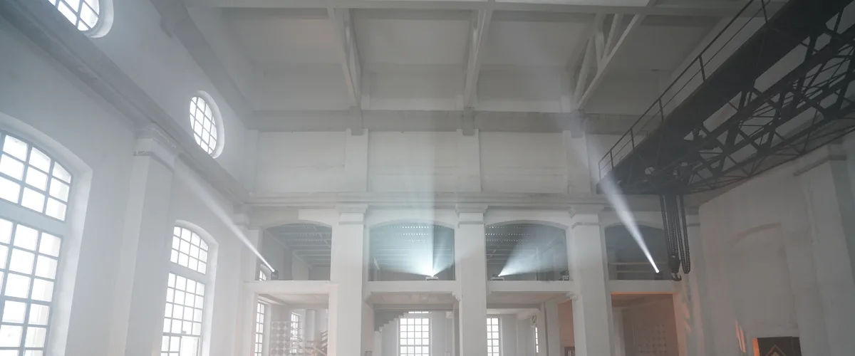 Interno della ex centrale termoelettrica di Daste e Spalenga, Bergamo — spazio industriale vuoto con fasci di luce, carroponte, finestre ad arco e oblò, prima dell'intervento SUONO E LUCE