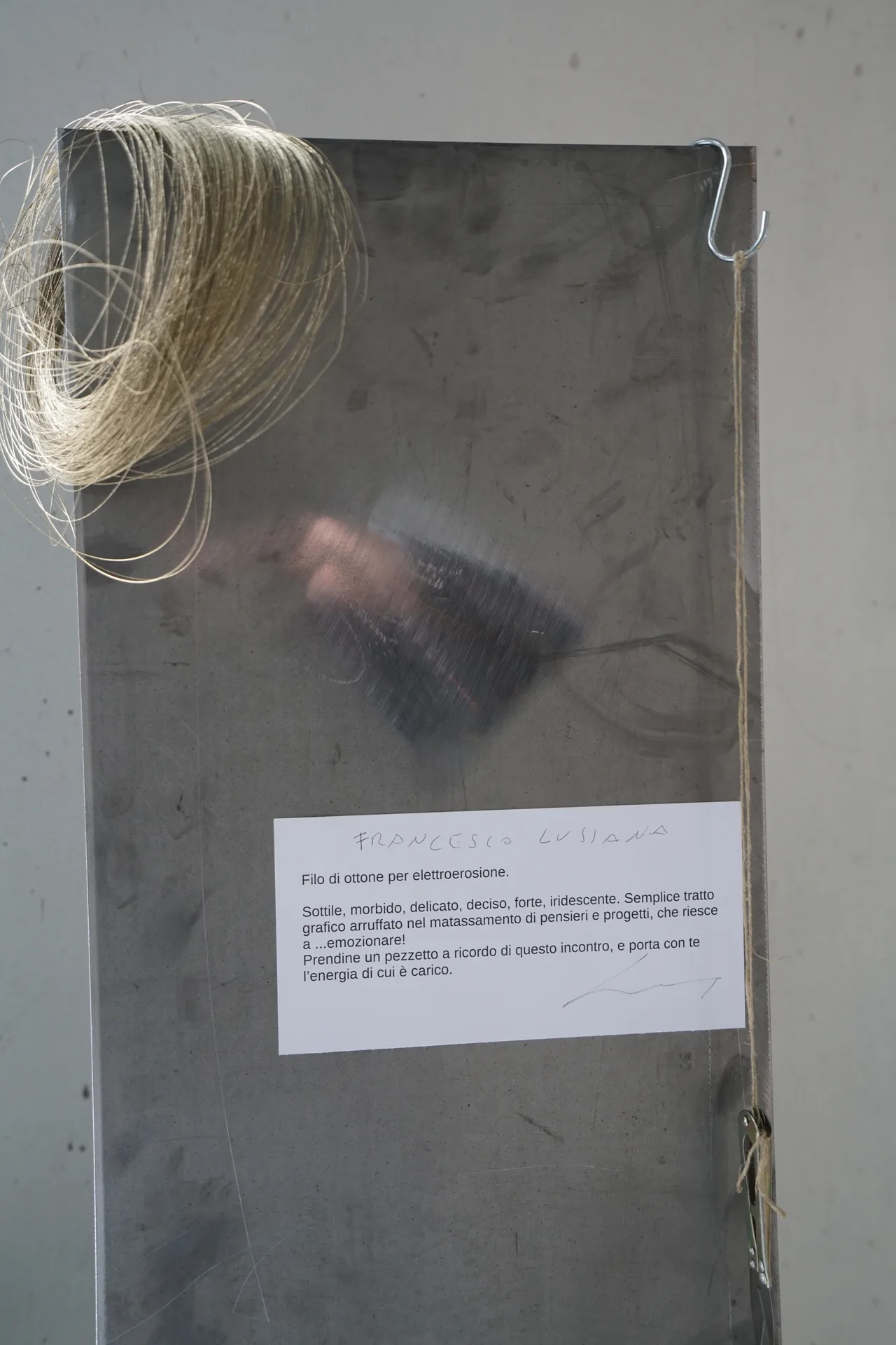 Filo d'ottone per elettroerosione con cartellino esplicativo — il talismano meccanico regalato ai visitatori di Civiltà Industriale, SUONO E LUCE