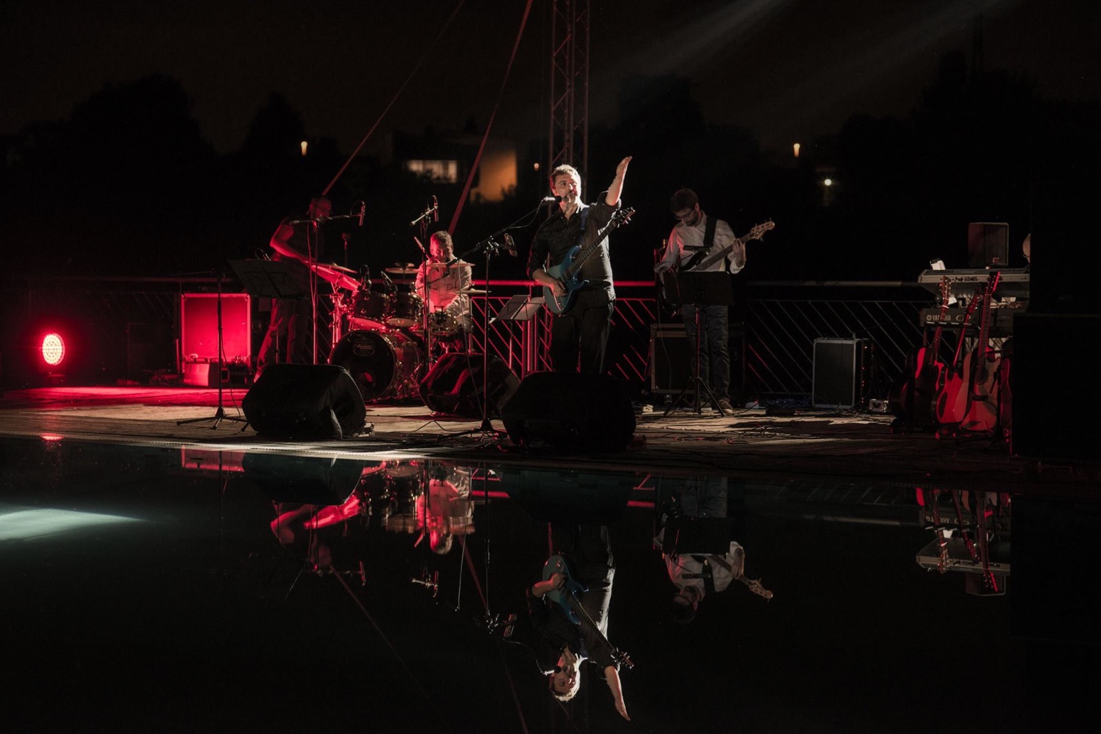 Band campo largo con riflesso rosso sull'acqua — light design per concerto all'aperto, Note sull'Acqua Pavia, SUONO E LUCE