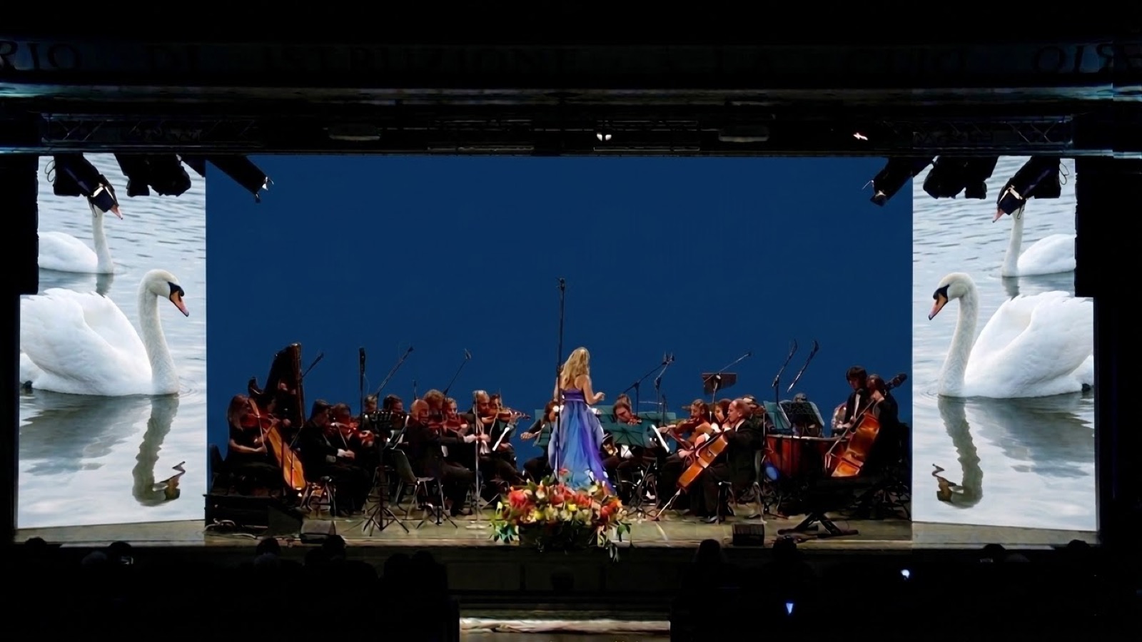 Orchestra Ars Armonica con cigni proiettati sulle quinte e fondale blu — video scenografia acquatica, Concerto per la Natura Bergamo 2022, SUONO E LUCE