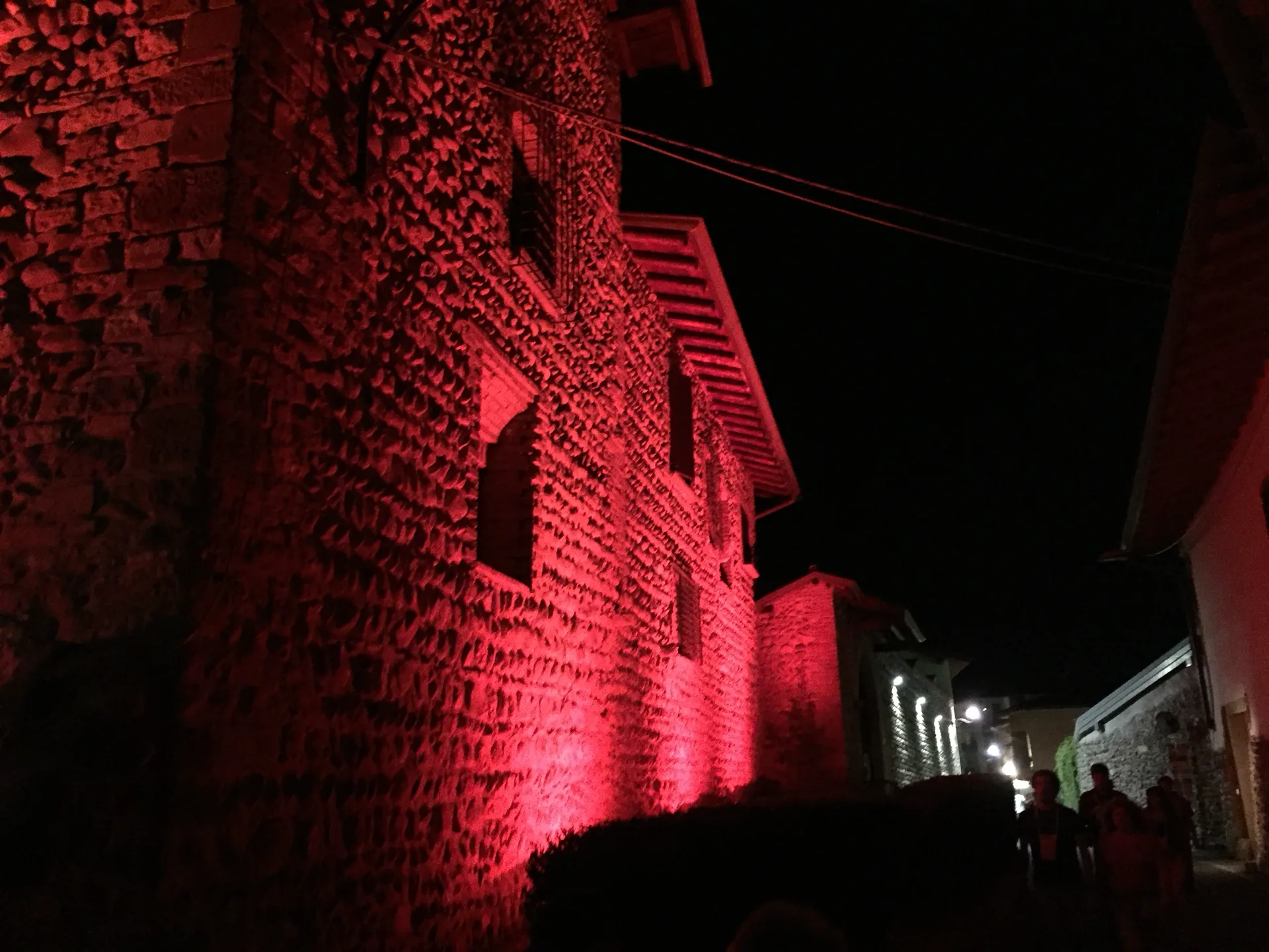 Vicolo di Rosciate con facciate in pietra illuminate di rosso durante la Festa del Moscato di Scanzo — SUONO E LUCE