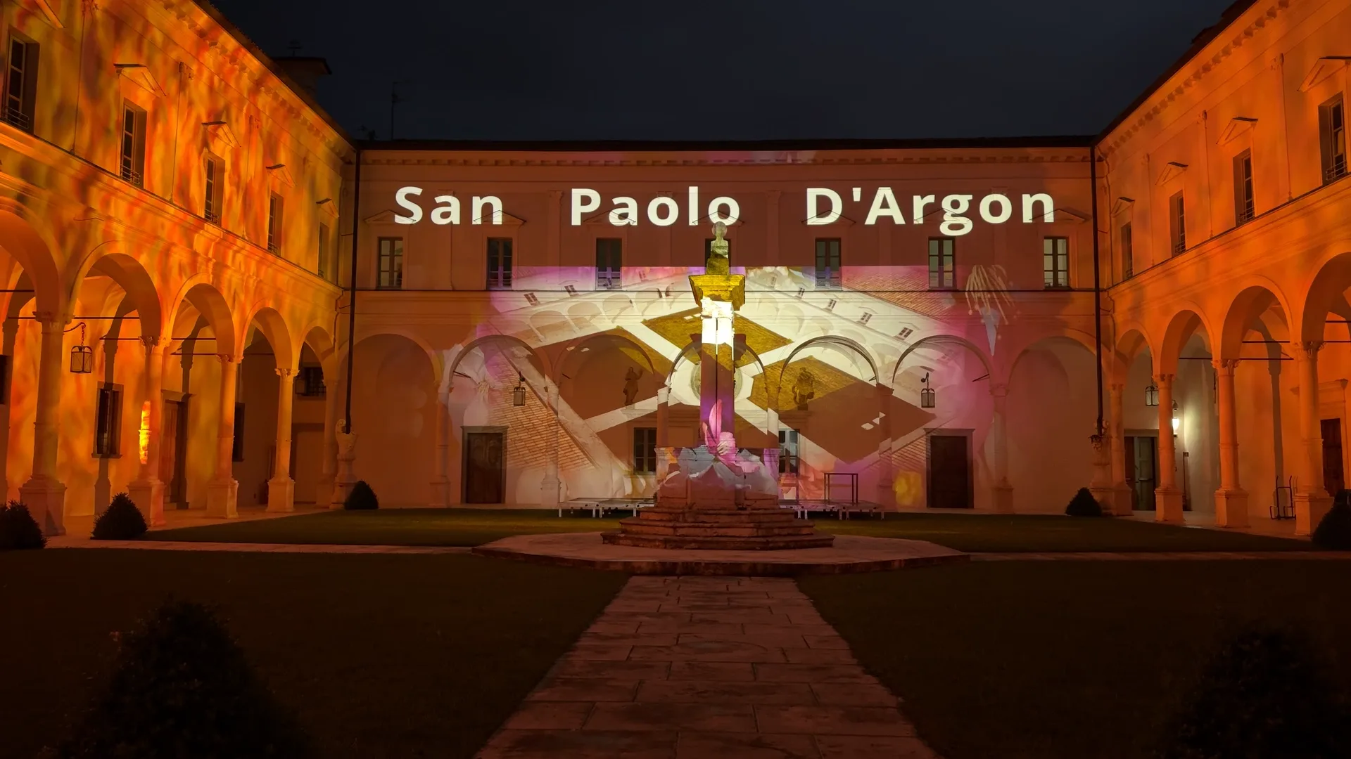 Scritta San Paolo D'Argon proiettata sulla facciata del chiostro con orologio — apertura dello spettacolo di videomapping architetturale, Abbazia di San Paolo d'Argon, SUONO E LUCE